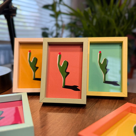 Set of colorful picture frames with cactus designs on a wooden surface.